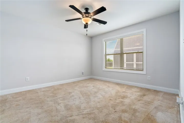 Well-lit room featuring soft carpeting, a ceiling fan.