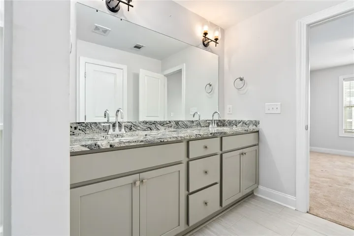Double vanity with sleek granite counters provides ample space and elegant appeal.