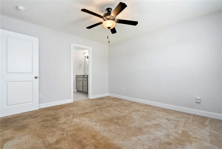 A well-lit bedroom features plush carpeting and convenient access to a private bath.