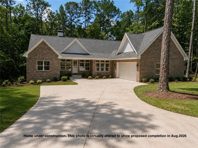 A newly constructed brick home with a spacious driveway and attached garage, nestled among mature trees.