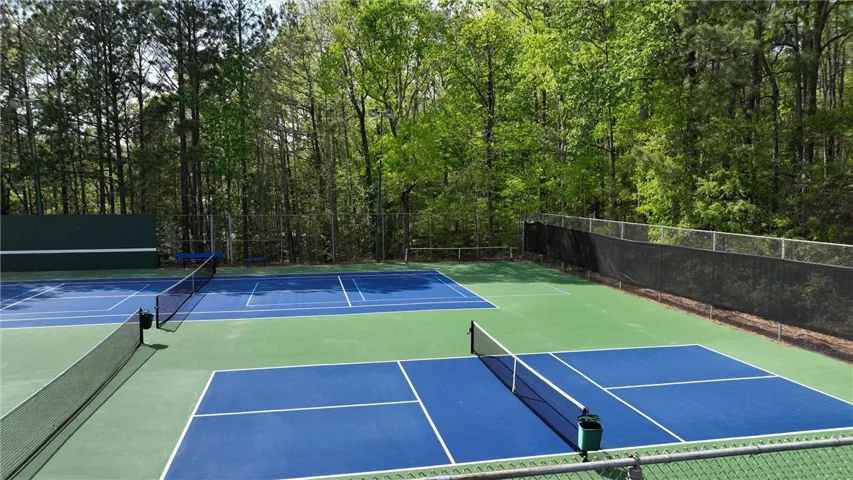 Two vibrant blue and green pickleball courts offer active recreation amidst a wooded backdrop.