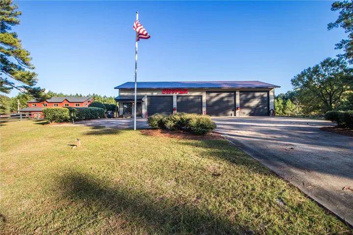 A flag proudly waves before a spacious garage with multiple bays and a distinct architectural profile.