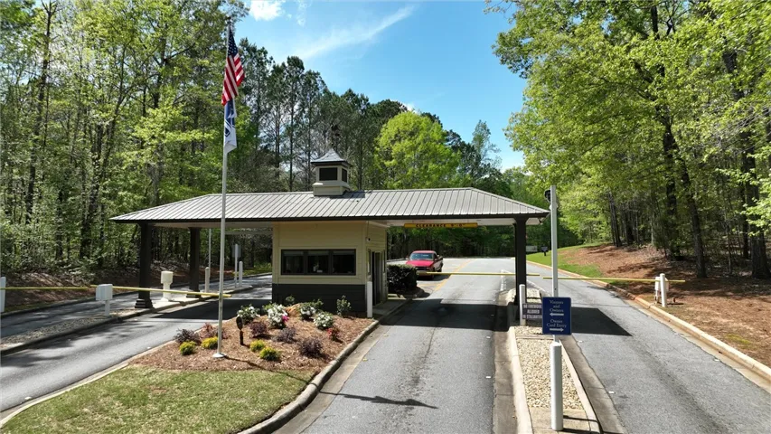 A secure gated entry welcomes residents, framed by lush trees under a vibrant sky.