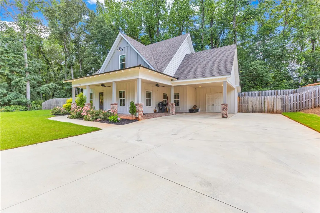A charming façade with a broad concrete driveway and a welcoming front porch.