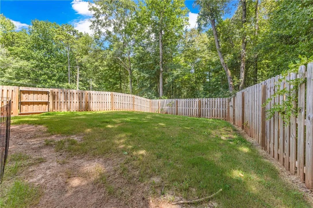 Secure, private yard with wooden fencing backs onto a verdant, wooded landscape.