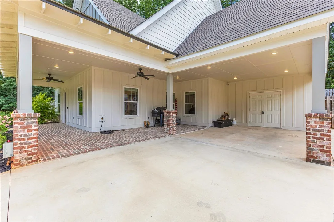 A spacious covered patio with brick columns and recessed lighting offers an inviting outdoor retreat.