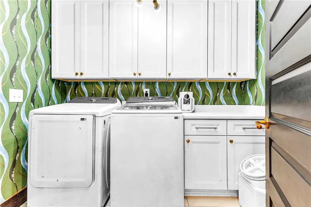 Functional laundry zone with pristine white appliances and ample storage cabinetry.