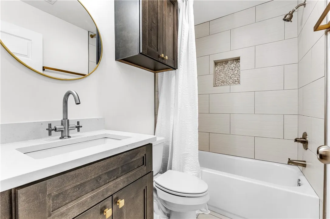 A well-appointed bathroom features a modern vanity with a sleek sink, alongside a clean bathtub with stylish tiled walls.