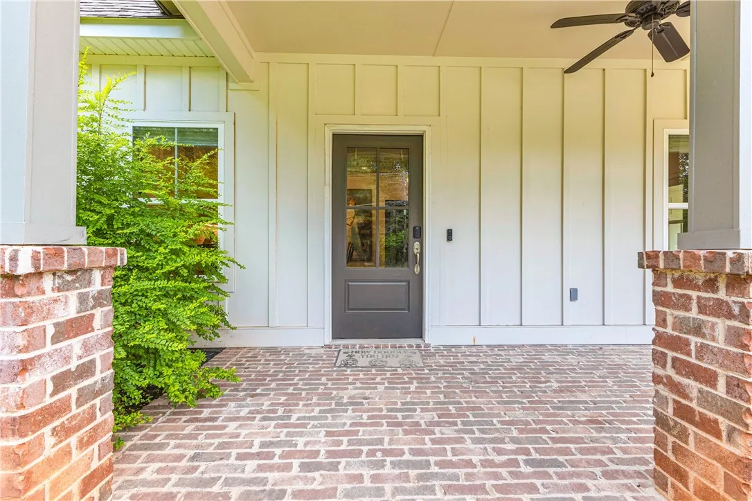 A welcoming front porch features a brick floor, board-and-batten siding, and a ceiling fan for comfort.