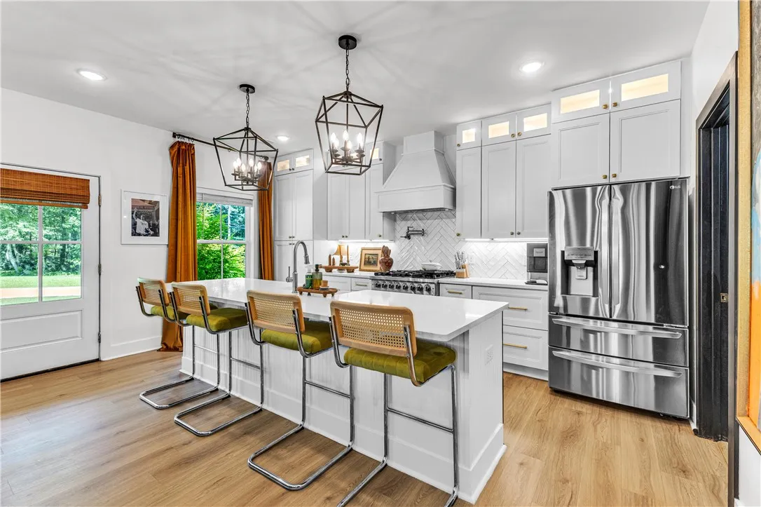 A contemporary kitchen features bright cabinetry, an expansive island with seating, and modern appliances perfect for culinary pursuits.