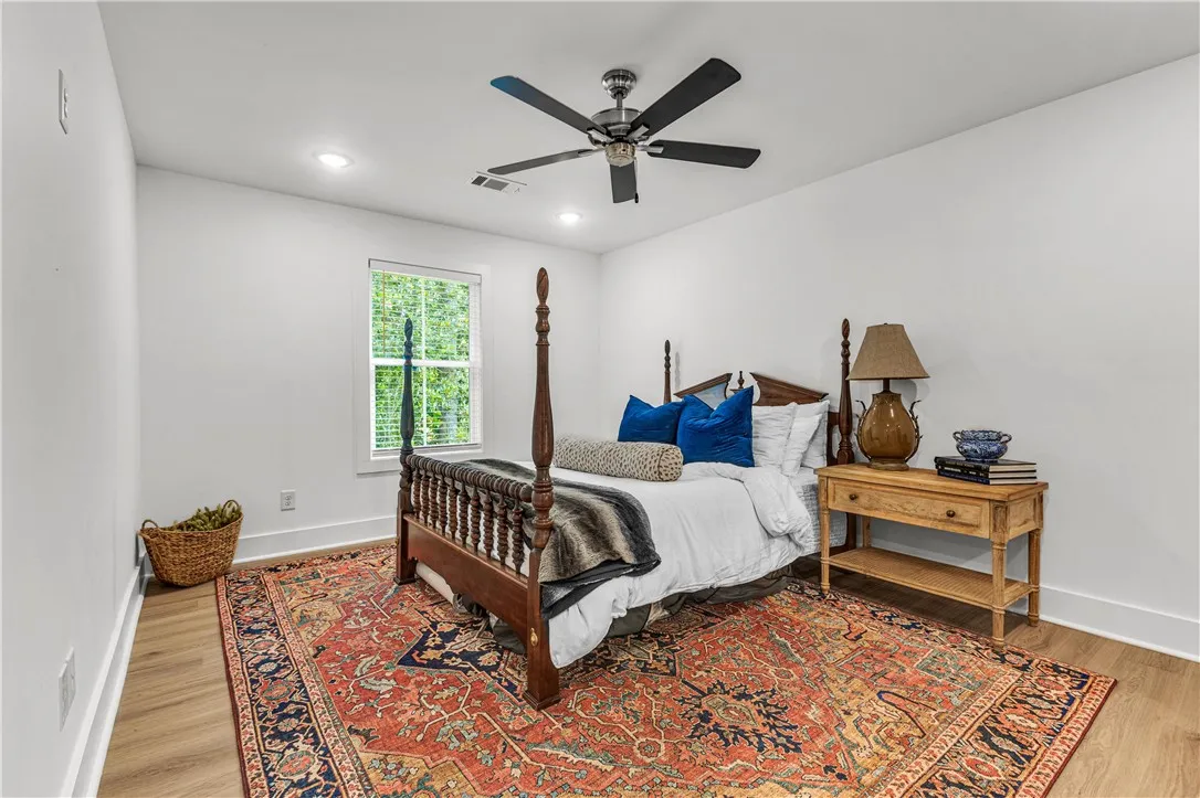 A well-lit primary bedroom features a classic four-poster bed and durable hardwood flooring.