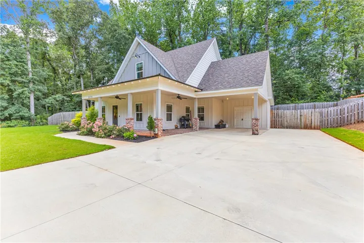 A charming façade with a broad concrete driveway and a welcoming front porch.