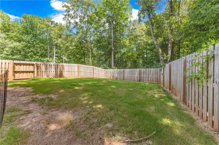 Secure, private yard with wooden fencing backs onto a verdant, wooded landscape.