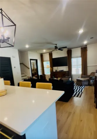 A well-lit living area features warm wood flooring and an inviting ambiance, perfect for gatherings.