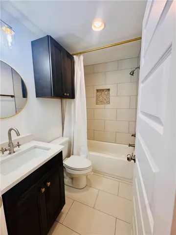 A pristine bathroom features a classic shower-tub combination and modern vanity.