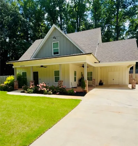 A charming residence with a covered front porch, brick accents, and a wide driveway offers welcoming curb appeal.