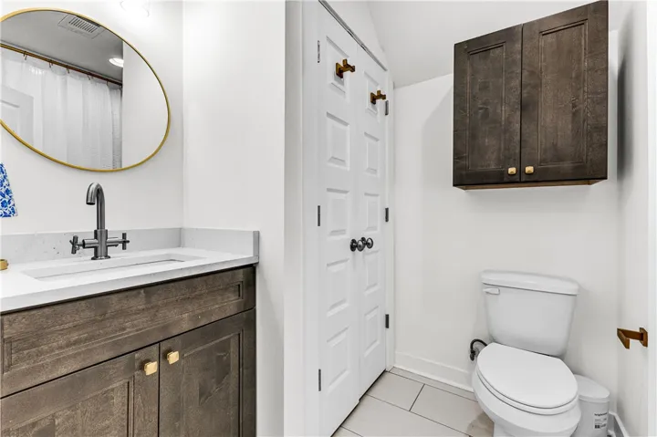 Functional full bathroom featuring a sleek vanity, an overhead cabinet, and a water closet.