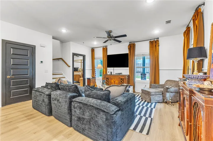 Natural light illuminates this living area featuring wood flooring and a classic ceiling fan.