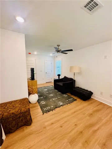 Natural wood flooring complements this inviting living area with a contemporary ceiling fan.