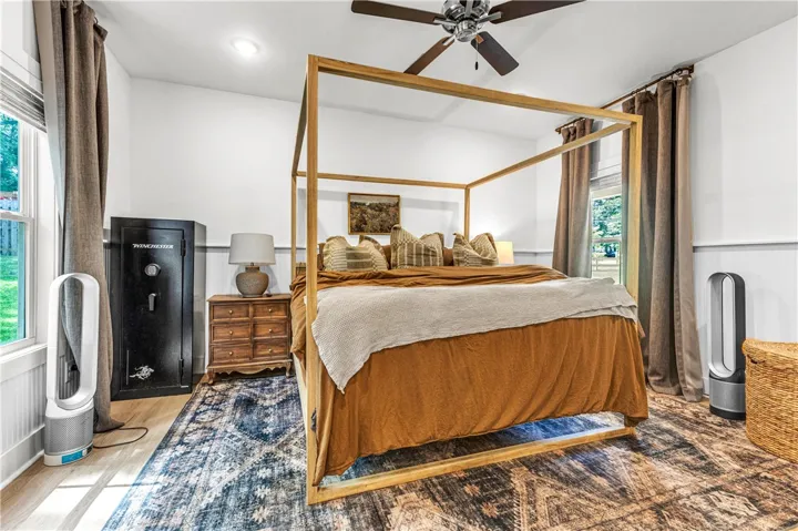 A well-lit bedroom features hardwood floors and a striking four-poster bed, creating a serene personal retreat.