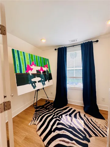 Blends a sleek hardwood floor with recessed lighting and natural illumination from a large window.