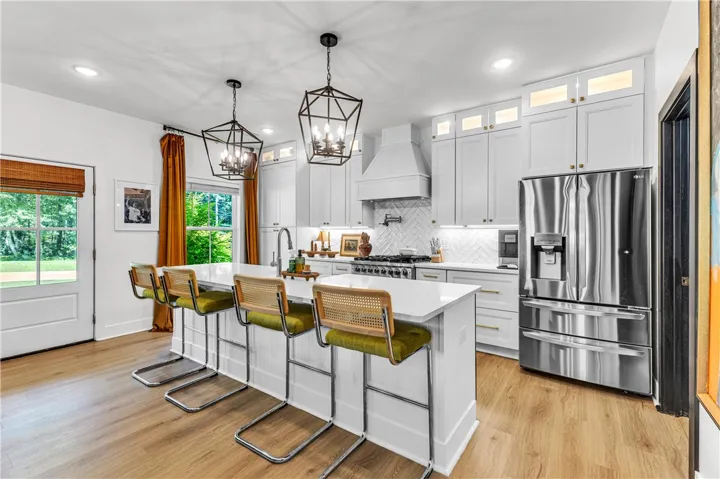 A contemporary kitchen features bright cabinetry, an expansive island with seating, and modern appliances perfect for culinary pursuits.