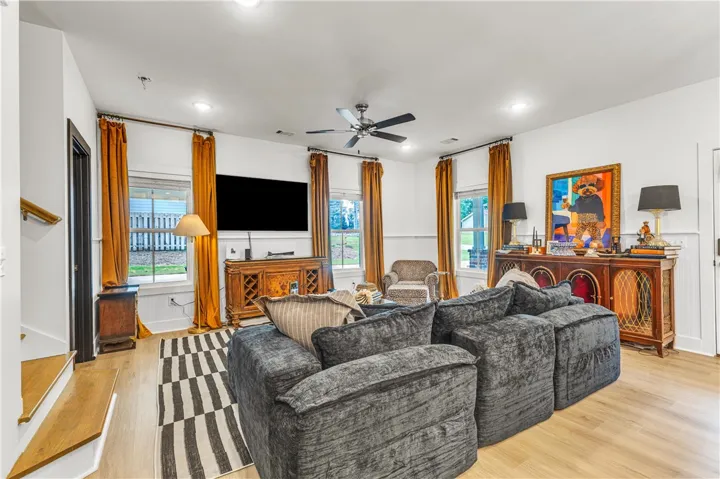 A naturally illuminated living room features light hardwood flooring and recessed ceiling lights for a warm glow.