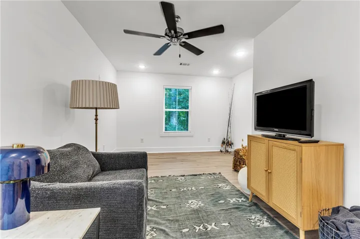 Bright living space showcasing a window overlooking verdant foliage and a sleek ceiling fan.