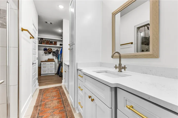 A well-appointed bathroom vanity with ample storage offers seamless access to a spacious walk-in closet.