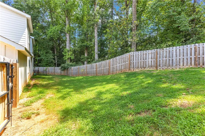 A fully fenced backyard with a gently sloping lawn offers a private, verdant outdoor retreat.