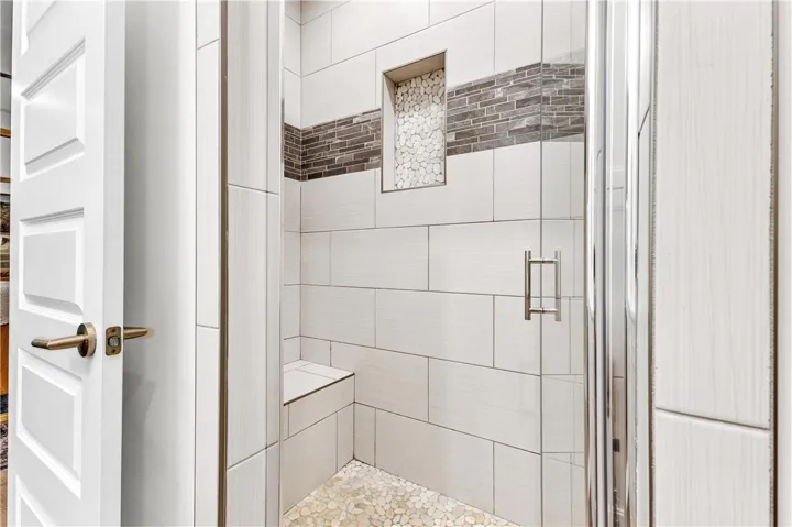 A well-appointed shower features stylish tile work and a convenient built-in bench.