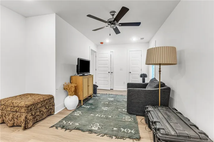 A quiet living area features light wood flooring and a classic ceiling fan, perfect for relaxation.