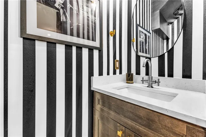 Bold striped walls create a distinctive backdrop for the vanity with a sleek countertop and modern fixtures.