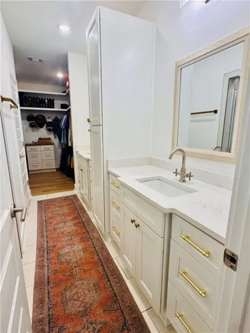 A well-appointed vanity with generous counter space, bright lighting, and a well-organized walk-in closet beyond.