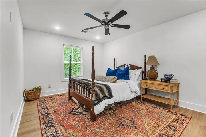 A well-lit primary bedroom features a classic four-poster bed and durable hardwood flooring.