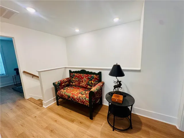 A quiet landing offers a cozy spot with rich wooden flooring and clear recessed lighting.
