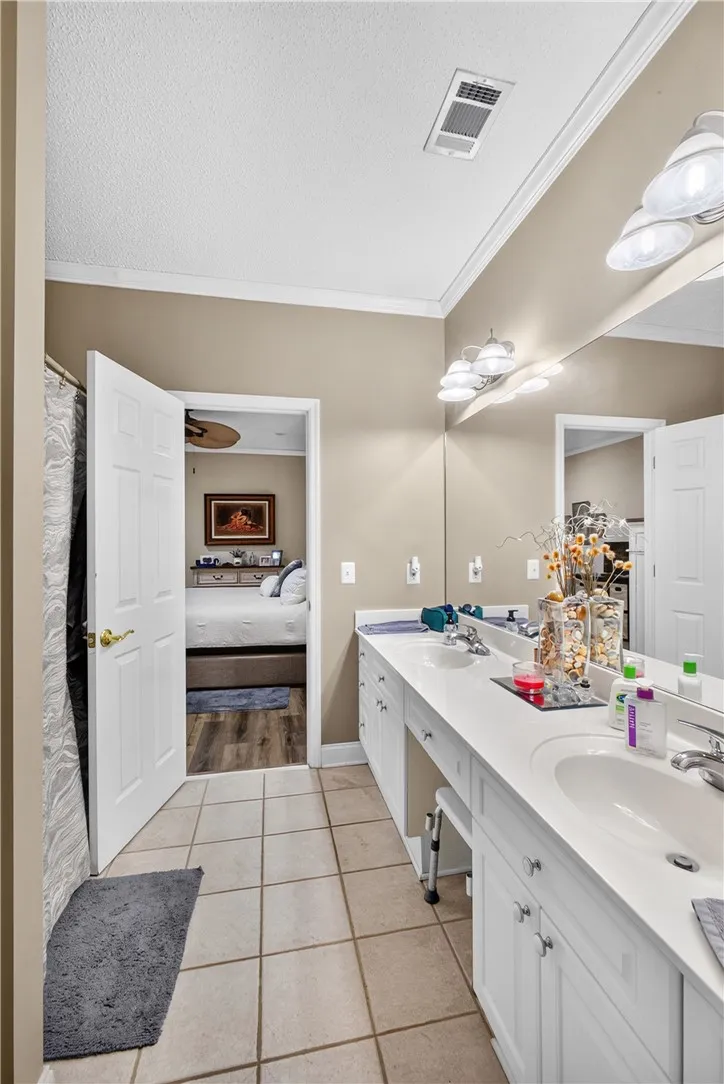 A well-appointed bath features a double vanity and a neutral color palette, offering a seamless connection to the adjacent bedroom.