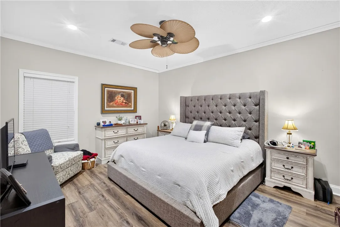 Relax in a generously proportioned bedroom featuring wood flooring and a refreshing ceiling fan.
