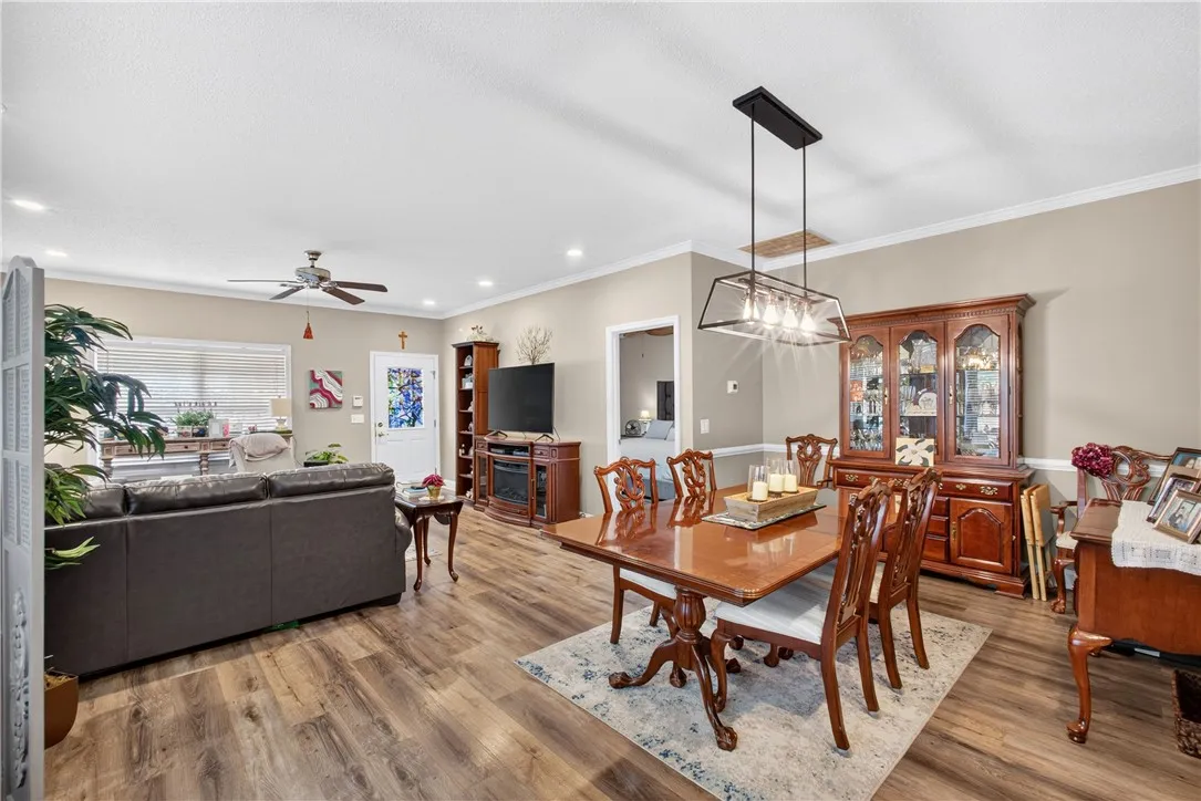 Laminate flooring throughout connects the living room to a dining area with a modern chandelier.