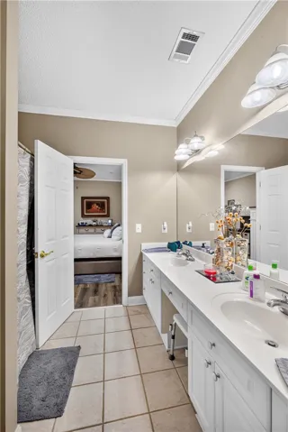 A well-appointed bath features a double vanity and a neutral color palette, offering a seamless connection to the adjacent bedroom.
