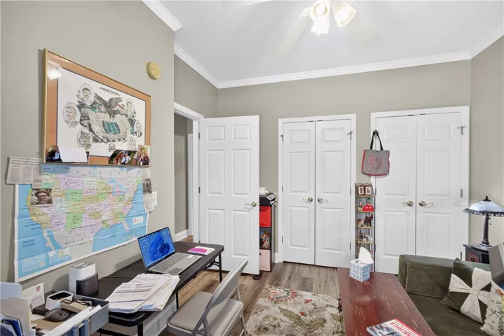 Bedroom currently used as an office featuring light-toned walls and elegant crown molding.