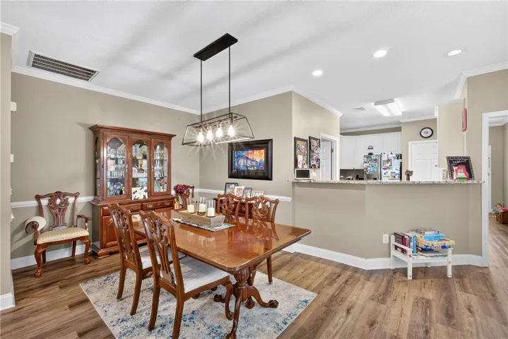 Elegant crown molding accents this dining space, featuring rich hardwood flooring and an open flow to the kitchen.
