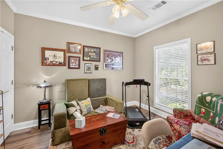 An inviting interior space, bathed in natural light, offers a comfortable retreat with crown molding and sturdy wood flooring.