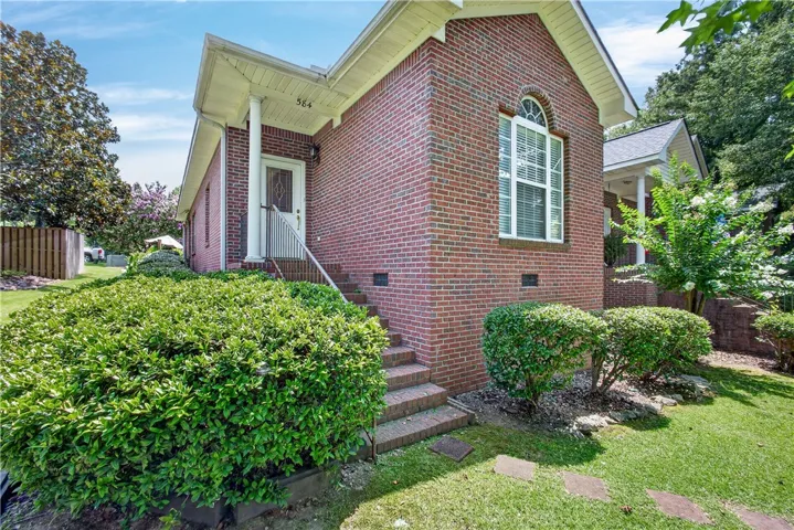 A classic brick exterior with a welcoming porch and vibrant green landscaping.