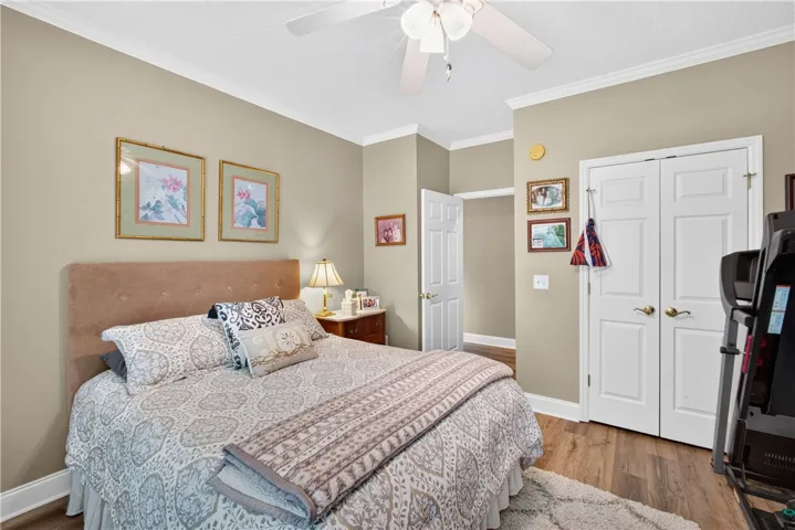Hardwood-style flooring and crown molding create a classic bedroom retreat.