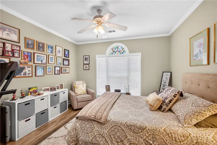 Relax in this well-lit bedroom featuring a ceiling fan and elegant crown molding.