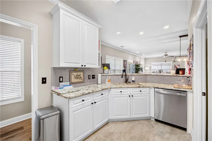 A well-appointed kitchen boasts sleek white cabinetry, gleaming granite counters, and a seamless flow into the living area.