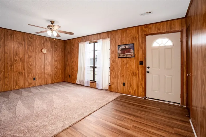 A welcoming entry featuring warm wood paneling and a blend of plush carpeting with rich hardwood flooring.