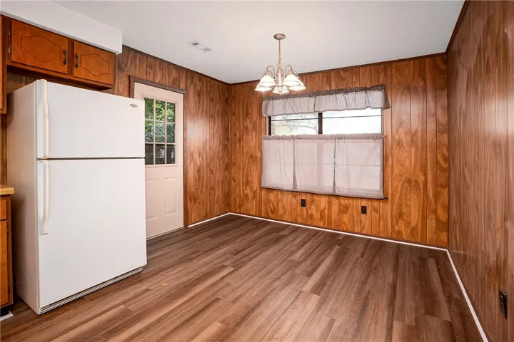 A well-lit dining space showcases warm wood paneling and durable plank flooring.