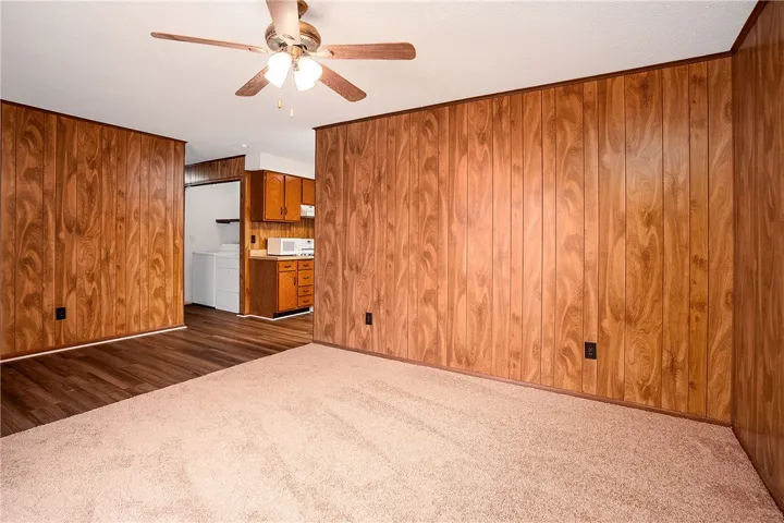 A classic living space offers a cozy feel, featuring wood-paneled walls and a ceiling fan for comfort.